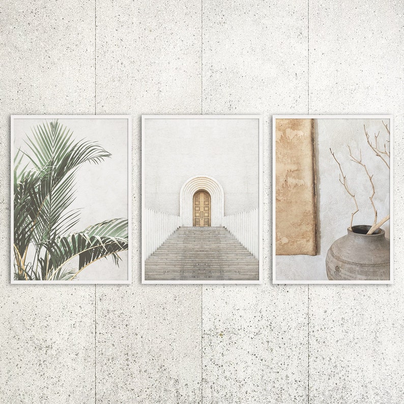 May include: Three framed prints with minimalist designs. The first print features a green palm leaf against a white background. The second print shows a white archway with a wooden door and steps leading up to it. The third print has a brown background with a dried branch and a brown vase.