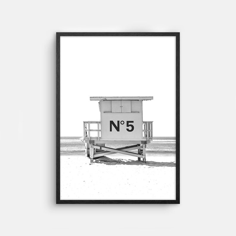 Puede incluir: Fotograf&iacute;a en blanco y negro de una caseta de salvavidas en una playa. La caseta est&aacute; numerada "N&deg; 5".