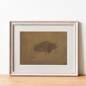 K&ouml;nnte beinhalten: Ein gerahmter Druck eines braunen Bisons, der in einer nebeligen, goldenen Landschaft steht. Der Bison blickt nach rechts und hat ein dunkelbraunes Fell. Der Hintergrund ist in einem weichen, ged&auml;mpften Braunton gehalten.