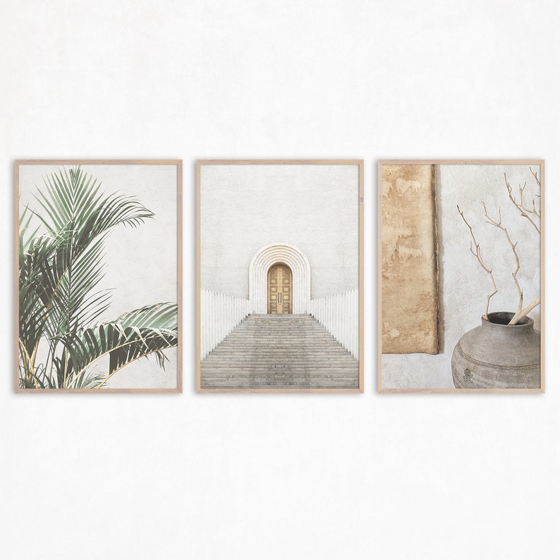 May include: Three framed prints with minimalist designs. The left print features a green palm leaf, the center print shows a white building with a doorway and steps, and the right print shows a brown vase with a dried branch.
