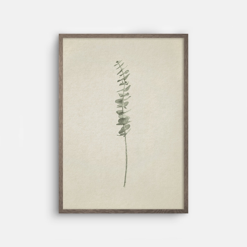 May include: A framed print of a watercolor painting of a single sprig of eucalyptus leaves on a beige background.