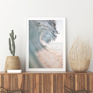 K&ouml;nnte beinhalten: Ein Foto einer gro&szlig;en Welle, die im Meer bricht. Die Welle ist hellblau und gr&uuml;n, das Wasser ist hellblau. Die Welle bricht &uuml;ber einen Sandstrand.