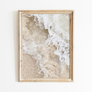 May include: A framed photograph of a beach scene with white foamy waves crashing on the sand.