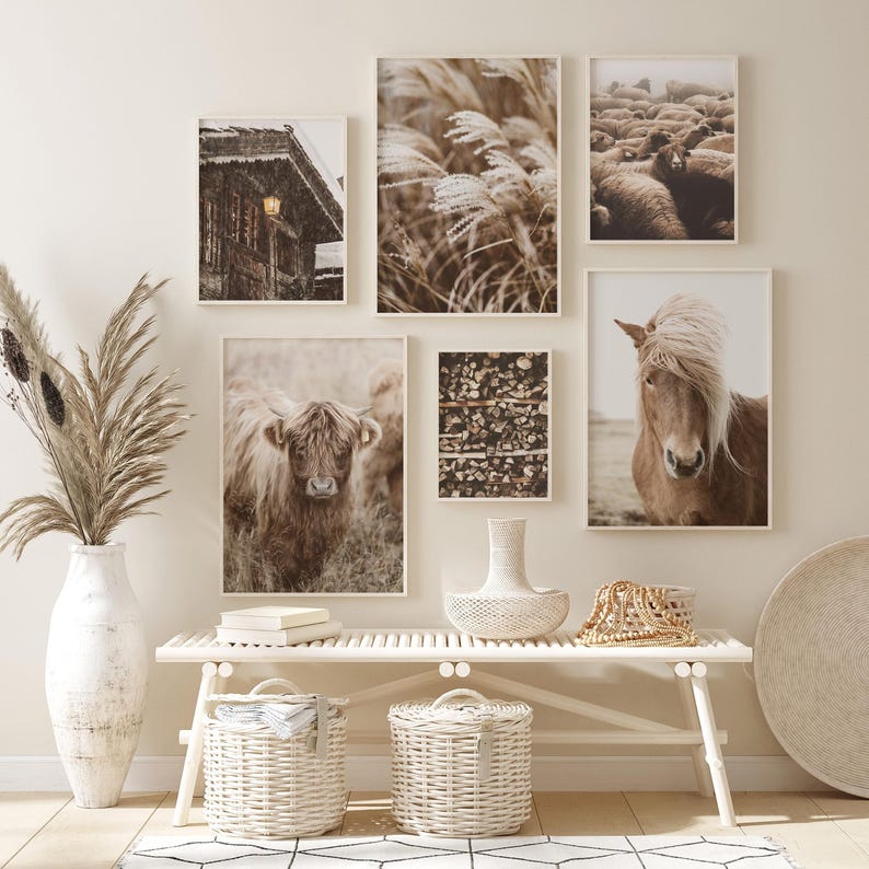 May include: A gallery wall featuring framed art prints with a rustic, farmhouse aesthetic. The prints depict scenes of nature, including a Highland cow, a horse, and a field of tall grass. The color palette is neutral with warm tones.
