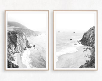 May include: Two black and white photographs of a rocky coastline with crashing waves and a sandy beach. The photos are framed in natural wood.