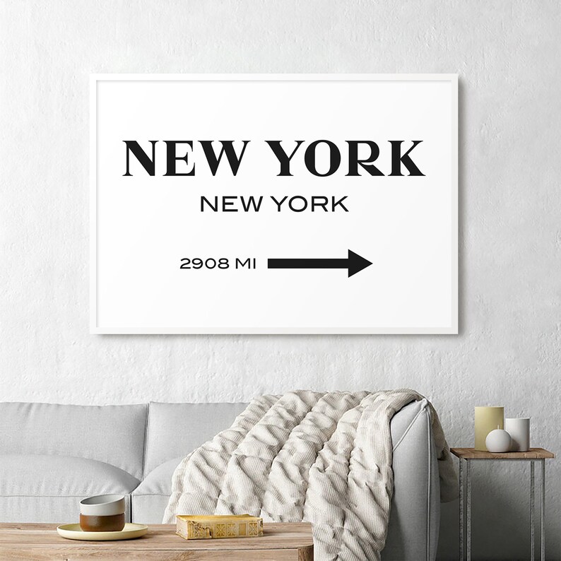May include: A rectangular wall art print featuring the text NEW YORK in large black serif font, followed by NEW YORK in smaller sans-serif font, and the text 2908 MI with a black arrow pointing to the right, all on a white background.