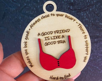 May include: A wooden ornament with a red bra design and the text "A good friend is like a good bra - Makes you look good! - Always close to your heart - There to support you - Hard to find".
