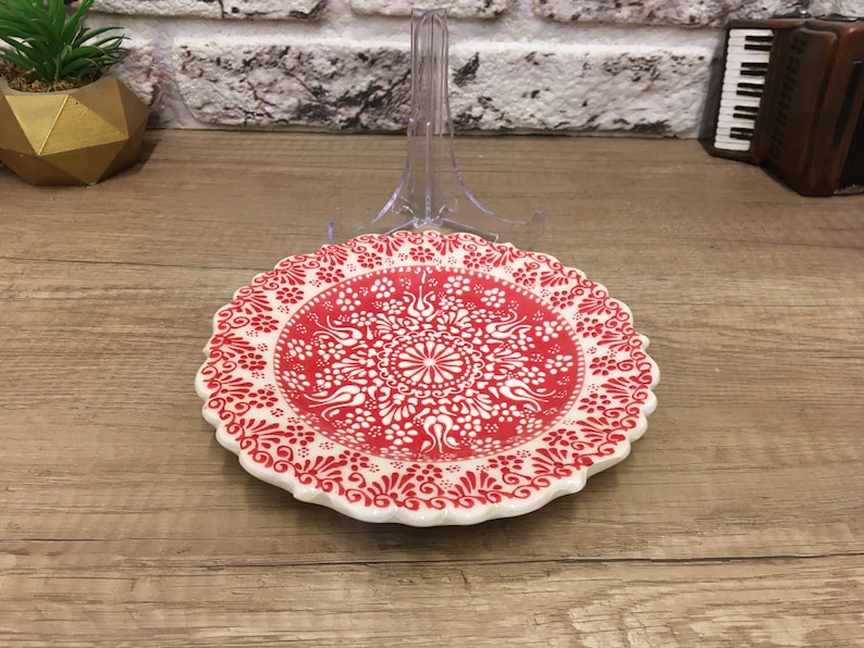 Puede incluir: Un plato de cer&aacute;mica blanco con un dise&ntilde;o floral rojo y blanco. El plato tiene un borde festoneado y est&aacute; decorado con un patr&oacute;n repetitivo de flores y hojas.