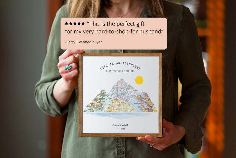 May include: A framed print with a mountain range design and the text "Life is an adventure, best traveled together". The mountains are made of a vintage map design with a yellow sun above them. The print is in a brown frame.
