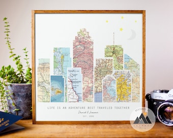 May include: A framed print with a cityscape made of vintage maps. The text "Life is an adventure best traveled together" is below the cityscape, along with the names "David & Jeanne" and "Est. 2000". The print is designed by "Journey Print Shop".