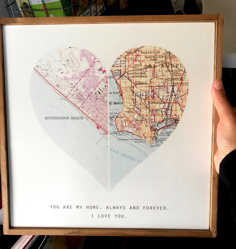 K&ouml;nnte beinhalten: Ein gerahmter Druck einer herzf&ouml;rmigen Karte von Los Angeles, Kalifornien. Die Karte ist in zwei H&auml;lften geteilt, wobei die linke Seite Huntington Beach und die rechte Seite die Stadt Los Angeles zeigt. Der Text "You are my home, always and forever. I love you." ist unter der Karte gedruckt.