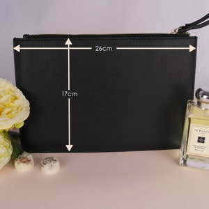 May include: Black zippered clutch bag with a textured finish. The bag measures 17 inches by 26 inches.