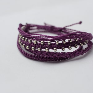 May include: A purple braided bracelet with silver beads.