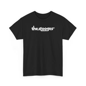 以下が含まれることがあります： 胸元に「the stooges」という白い文字がプリントされた黒い半袖Tシャツ。このグラフィックは、文字が連続した水平線でつながったスタイリッシュな連結フォントを使用しており、衣服の中央に配置されています。