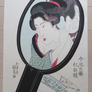 Puede incluir: Una estampa japonesa en madera que representa a una mujer mirando su reflejo en un espejo de mano. La mujer lleva un kimono tradicional y tiene el pelo recogido en un moño. El espejo es redondo y tiene un marco negro. La estampa está en tonos de azul, verde, rojo y negro.