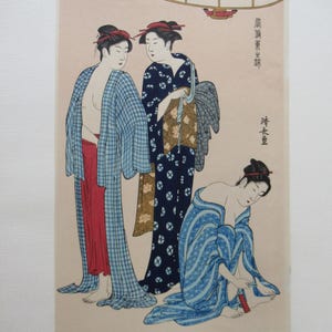 Puede incluir: Una impresión japonesa en madera que representa a tres mujeres con vestimenta tradicional. Una mujer está sentada, ajustándose el calzado. Las otras dos mujeres están de pie, una con un kimono azul estampado y otra con una túnica a cuadros azules.