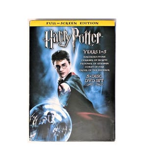 May include: A DVD box set featuring the first five Harry Potter films. The cover art shows Harry Potter with a wand, set against a blue background. The set includes "Sorcerer's Stone," "Chamber of Secrets," "Prisoner of Azkaban," "Goblet of Fire," and "Order of the Phoenix."