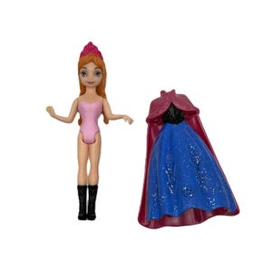 Pu&ograve; includere: Una bambola con i capelli rossi, un body rosa e stivali neri &egrave; in piedi accanto a un vestito blu e rosso. La bambola ha una corona rosa ed &egrave; in piedi. L'abito ha un mantello rosso.