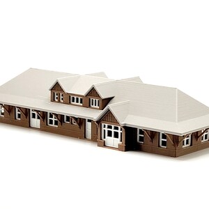 May include: A brown and white model train station with a gabled roof and multiple windows.