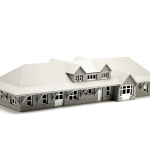 May include: A gray 3D printed model of a building with a gabled roof and multiple windows. The building has a porch with a railing and a door.