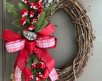May include: A Christmas wreath made of brown twigs with a red and white plaid bow and red berries with white accents.