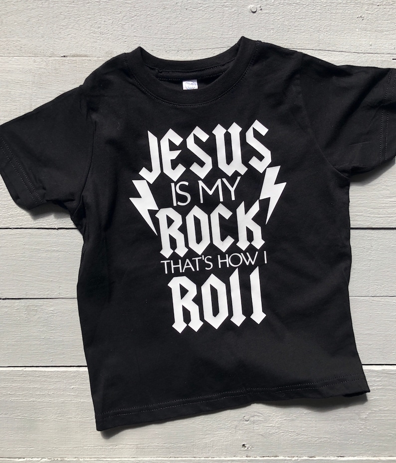 May include: Black t-shirt with white text that reads "Jesus is my rock, that's how I roll".
