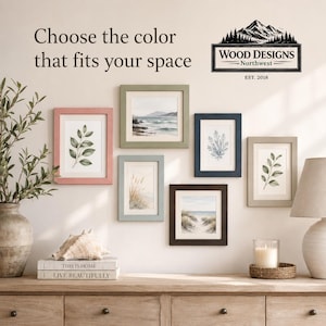K&ouml;nnte beinhalten: Pr&auml;sentation von gerahmten Kunstdrucken in verschiedenen Farben, darunter Rosa, Gr&uuml;n und Blau, mit botanischen und K&uuml;stenmotiven. Der Text "Choose the color that fits your space" wird &uuml;ber den Rahmen angezeigt. Das Logo von Wood Designs Northwest ist ebenfalls sichtbar.