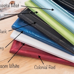May include: A stack of six picture frames in various colors, including colonial red, blossom white, evening navy, canyon black, key lime, and coastal mist.
