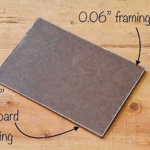 May include: A close-up of a 1/8" hardboard backing and a 0.06" framing glass. The hardboard is brown and the glass is clear.