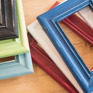 May include: Four picture frames stacked on top of each other. The top frame is blue, the next is white, the next is red, and the bottom frame is light blue.