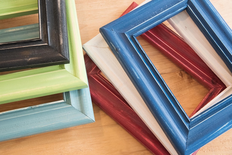 May include: Four picture frames stacked on top of each other. The top frame is blue, the next is white, the next is red, and the bottom frame is light blue.