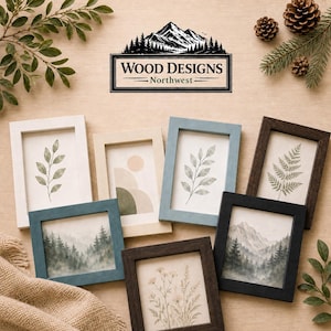 K&ouml;nnte beinhalten: Eine Sammlung gerahmter Kunstdrucke mit botanischen und Landschaftsmotiven. Die Rahmen sind in verschiedenen Farben erh&auml;ltlich, darunter Wei&szlig;, Blau und Braun. Das Logo von Wood Designs Northwest befindet sich oben, mit nat&uuml;rlichen Elementen wie Tannenzapfen und Gr&uuml;n.