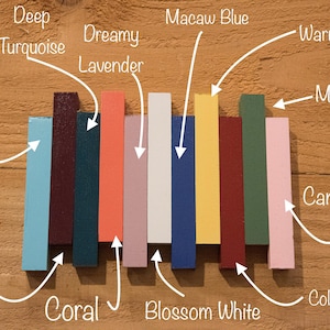 May include: A row of ten paint color samples, each labeled with a name. The colors are: Aqua, Aubergine, Coral, Dreamy Lavender, Blossom White, Macaw Blue, Warm Yellow, Moss Green, Colonial Red, and Candy Pink.
