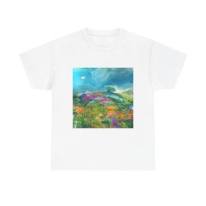 Puede incluir: Una camiseta blanca con una pintura abstracta colorida de un paisaje con un cielo azul, hierba verde y un solo árbol. La pintura tiene forma cuadrada y está centrada en la camiseta.