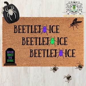 May include: A brown coir doormat with the words "BEETLEJ ICE" repeated three times, each line with a different colored beetle graphic. A black pumpkin and spiders decorate the top and bottom. The text "NEVER TRUST THE LIVING" is also present.