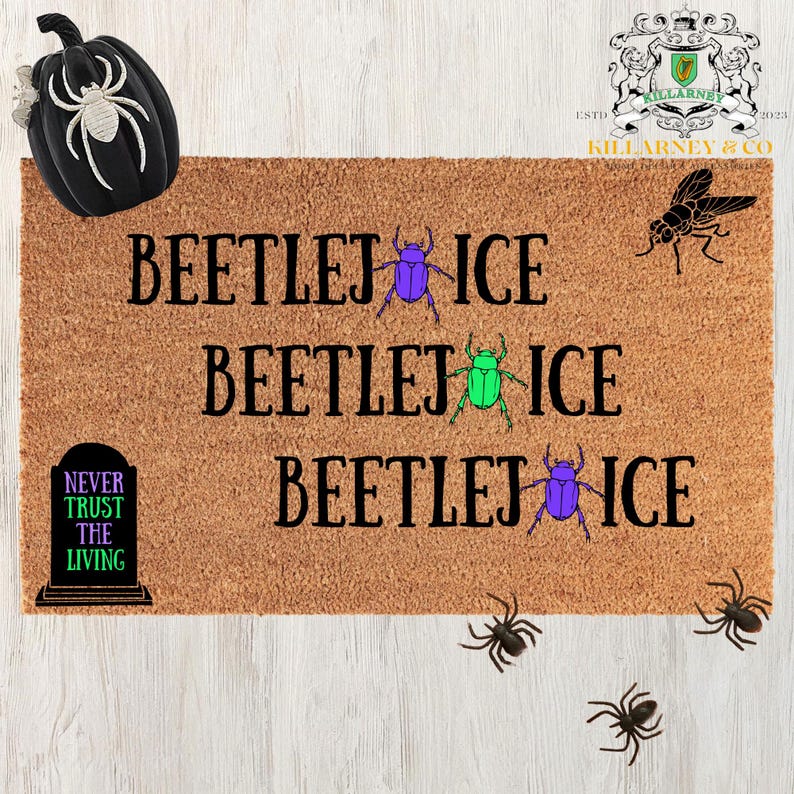 May include: A brown coir doormat with the words "BEETLEJ ICE" repeated three times, each line with a different colored beetle graphic. A black pumpkin and spiders decorate the top and bottom. The text "NEVER TRUST THE LIVING" is also present.