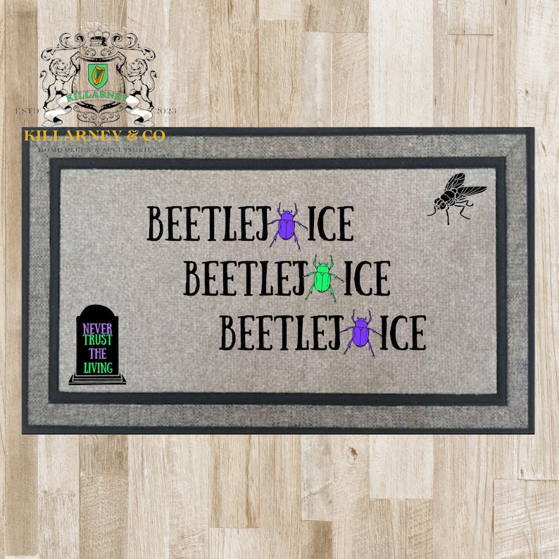 May include: Rectangular gray doormat with a dark gray border. The mat features the text "BEETLEJ ICE" repeated three times, with purple and green beetle graphics. A black fly graphic is in the upper right corner, and a tombstone graphic with the text "NEVER TRUST THE LIVING" is in the lower left corner.