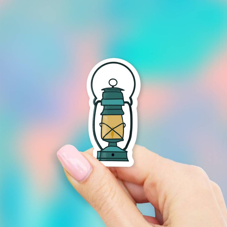 May include: A teal blue lantern sticker with a yellow flame inside. The sticker is on a white background.