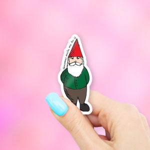 May include: A sticker featuring a cartoon gnome with a red hat and a white beard. The gnome is wearing a green shirt and brown pants. The sticker has the text "Gnomes made me do it" written on it.