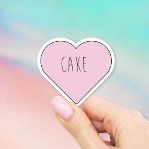 May include: Pink heart-shaped sticker with the word "CAKE" written in black.