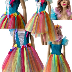 Pode incluir: Um vestido de tule arco-&iacute;ris com um corpete turquesa e um design branco brilhante. O vestido tem uma bainha alta-baixa e &eacute; decorado com flores coloridas. O vestido &eacute; perfeito para uma festa com tema de unic&oacute;rnio.