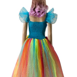 Pode incluir: Um vestido de tule arco-&iacute;ris com um corpete turquesa e mangas de tule azul combinando. O vestido tem um acabamento brilhante e &eacute; coroado com uma faixa de cabe&ccedil;a de unic&oacute;rnio arco-&iacute;ris.