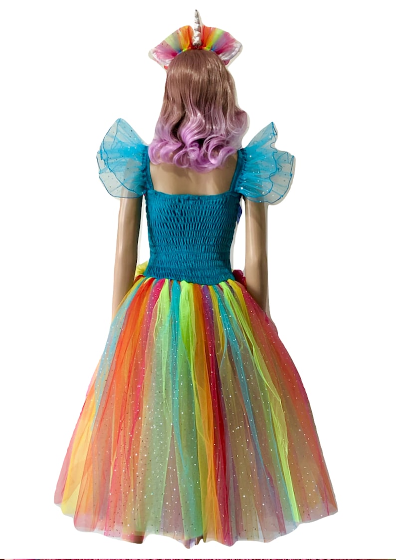 Pode incluir: Um vestido de tule arco-&iacute;ris com um corpete turquesa e mangas de tule azul combinando. O vestido tem um acabamento brilhante e &eacute; coroado com uma faixa de cabe&ccedil;a de unic&oacute;rnio arco-&iacute;ris.