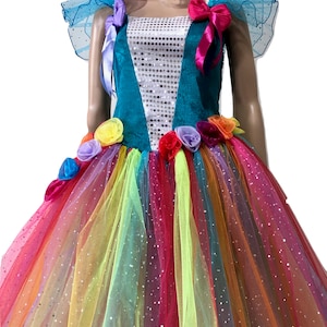 Pode incluir: Um vestido de tule turquesa e arco-&iacute;ris com corpete de lantejoulas e detalhes de flores. O vestido tem uma saia de tule arco-&iacute;ris com um acabamento brilhante.