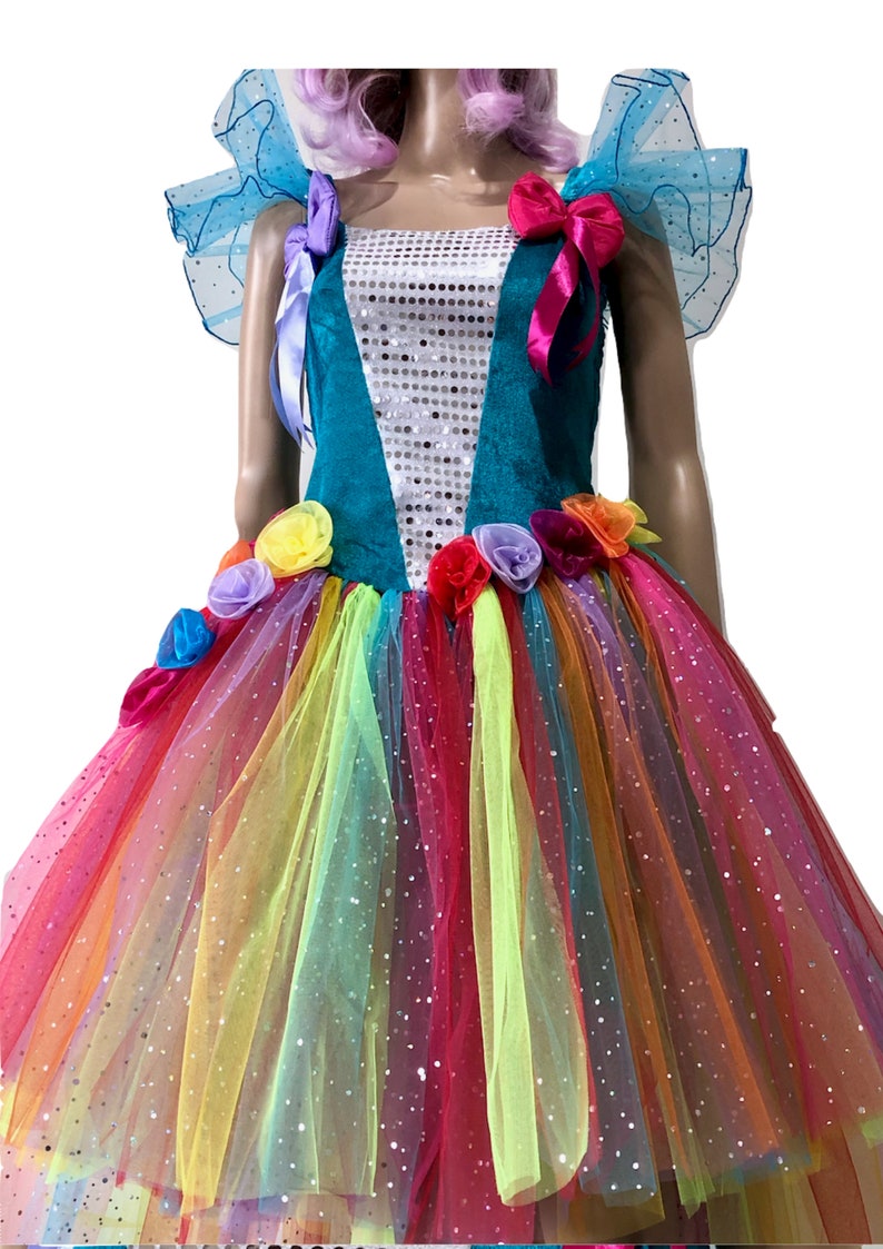 Pode incluir: Um vestido de tule turquesa e arco-&iacute;ris com corpete de lantejoulas e detalhes de flores. O vestido tem uma saia de tule arco-&iacute;ris com um acabamento brilhante.