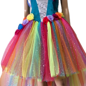Pode incluir: Um vestido de tule arco-&iacute;ris com um corpete turquesa e detalhes de lantejoulas. O vestido tem uma bainha alta-baixa e &eacute; decorado com flores de tecido coloridas.