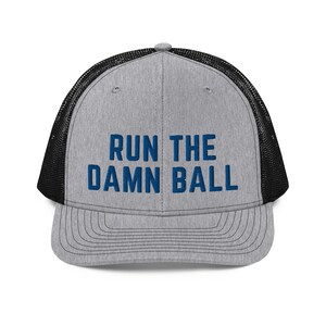 May include: A gray and black trucker hat with the text "RUN THE DAMN BALL" embroidered in blue.
