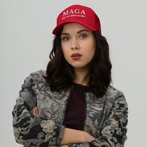 May include: A red baseball cap with a white embroidered logo that reads "MAGA MAKE THE ASSHOLE GO AWAY".