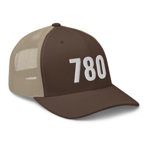 May include: A brown and tan trucker hat with a white mesh back. The front of the hat has the number 780 embroidered in white.