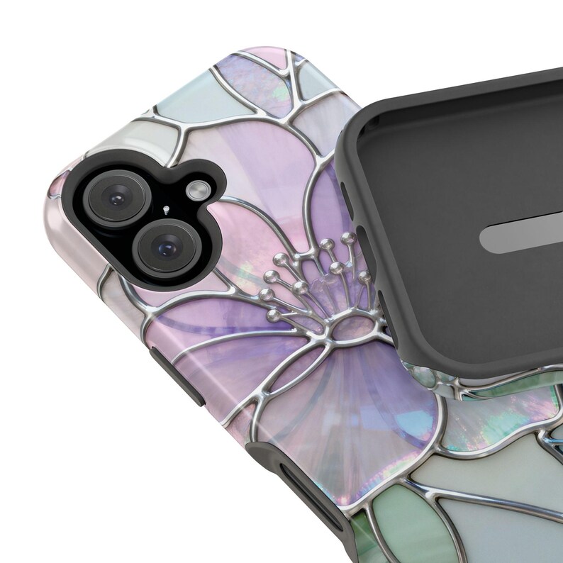 May include: A smartphone case with a floral design. The case features a stained-glass style flower in shades of purple, pink, and green, outlined with silver-coloured metal. The phone's camera lenses are visible. The case is partially open, revealing the black interior.